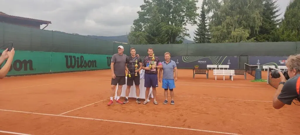 Vítězové turnaje Červená Voda Open 2023 s poháry na antukovém kurtu.