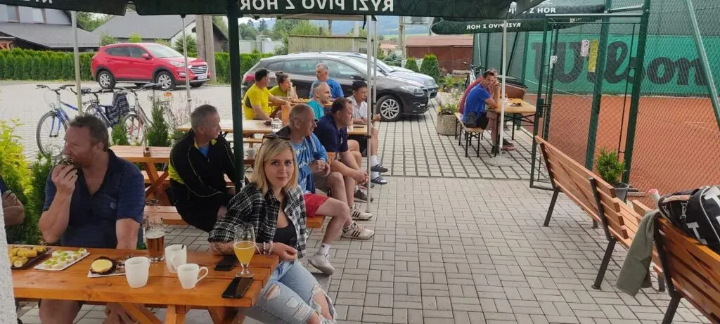 Hráči a hosté odpočívají u občerstvení vedle kurtů.