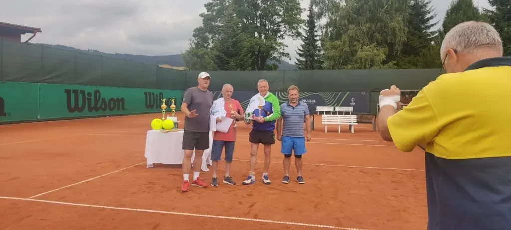 Pořadatel fotografuje oceněné hráčky a hráče na kurtu.